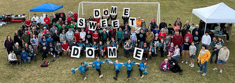 crowd holding Dome Sweet Dome signs
